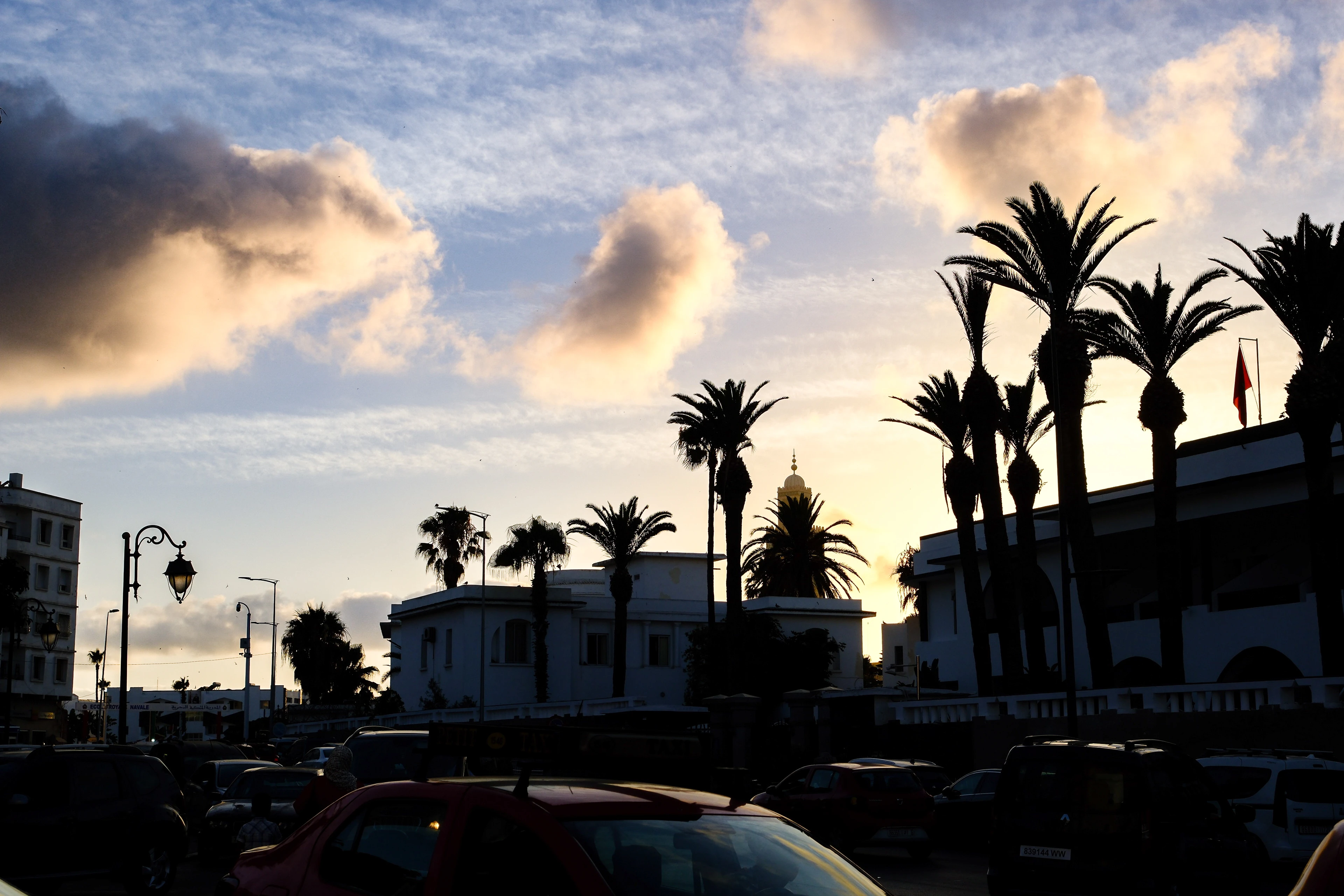 Palm trees and Casablanca buildings silhouetted beneath illuminated evening clouds