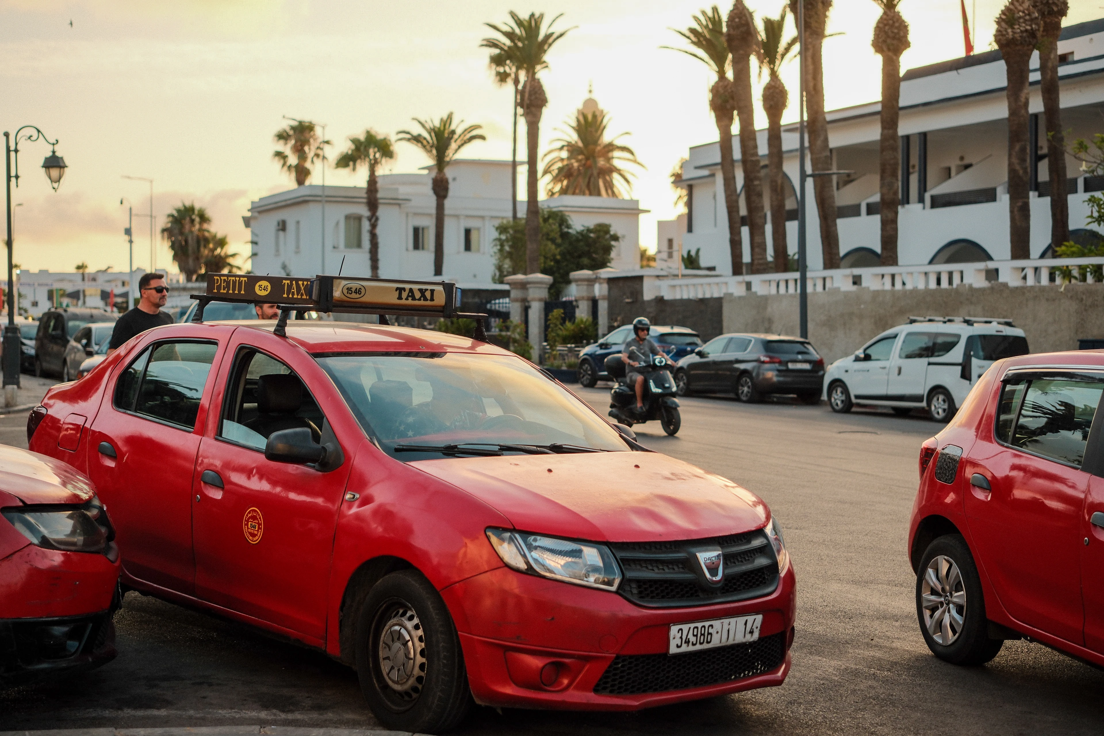 Red taxis gathered on a palm-lined Casablanca street at sunset