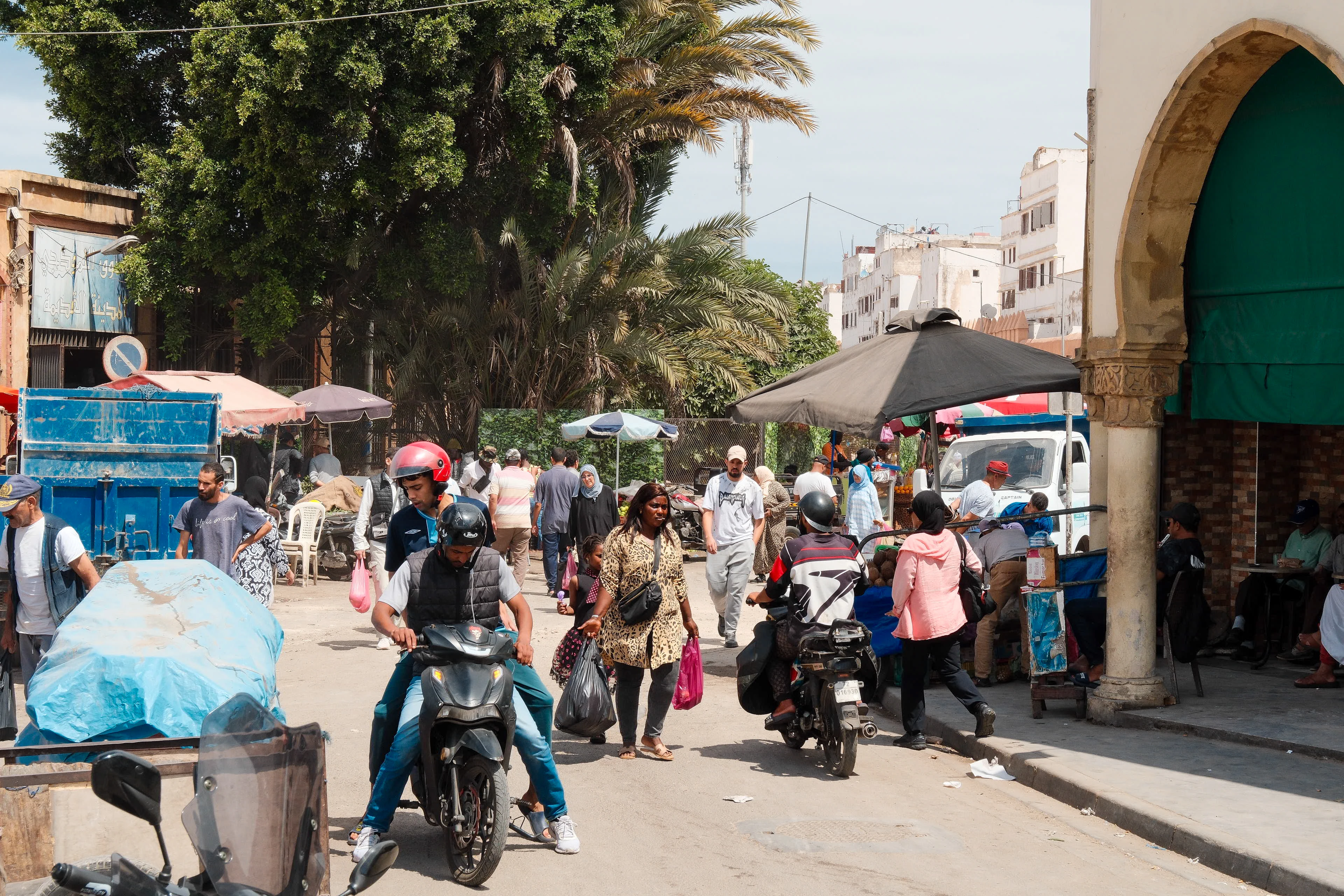Pedestrians and motorbikes move through a crowded Casablanca market street