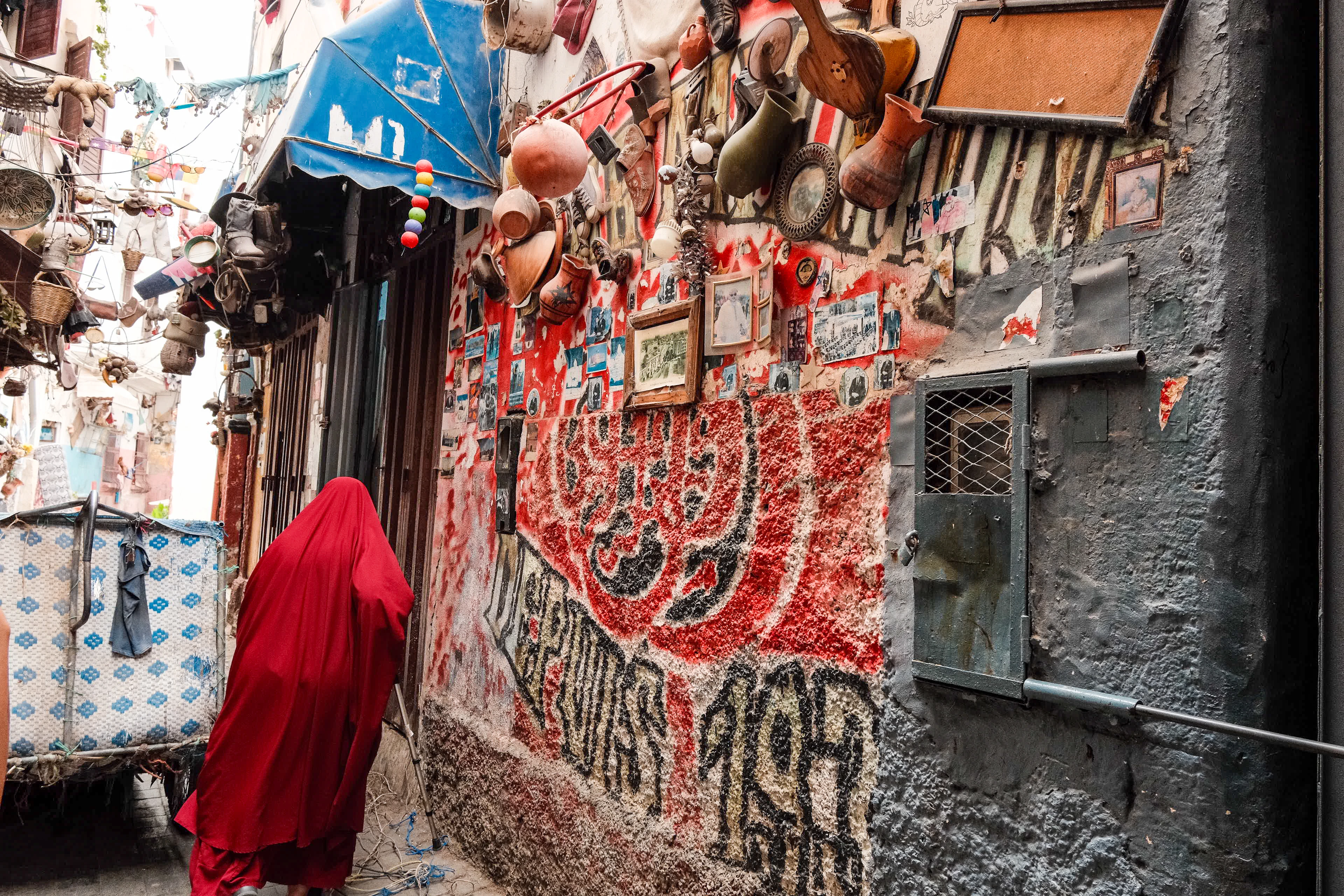 A figure in a red robe walks beside a densely painted market wall in Casablanca's medina
