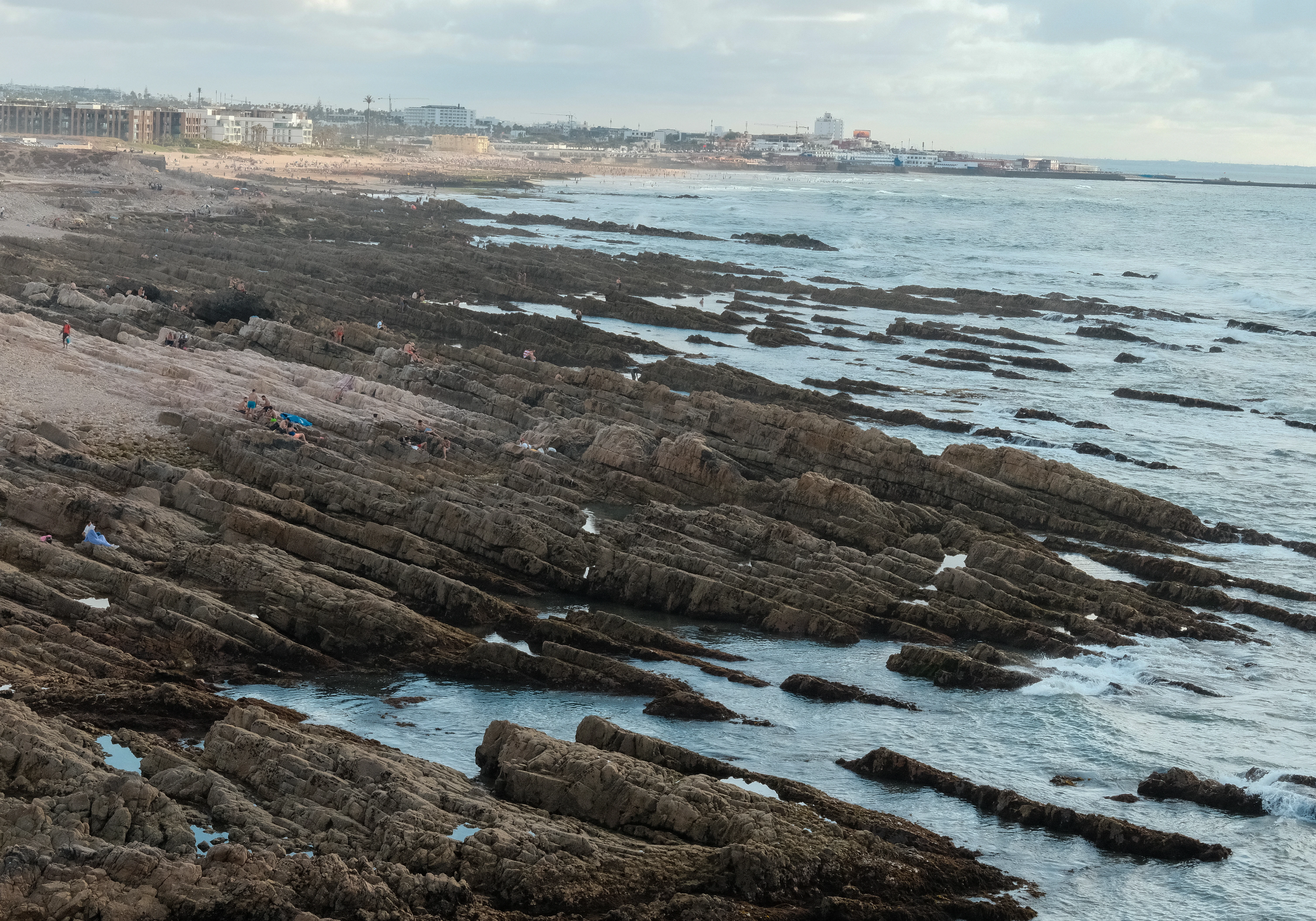 A wide view of Casablanca's rocky Atlantic shoreline and distant city