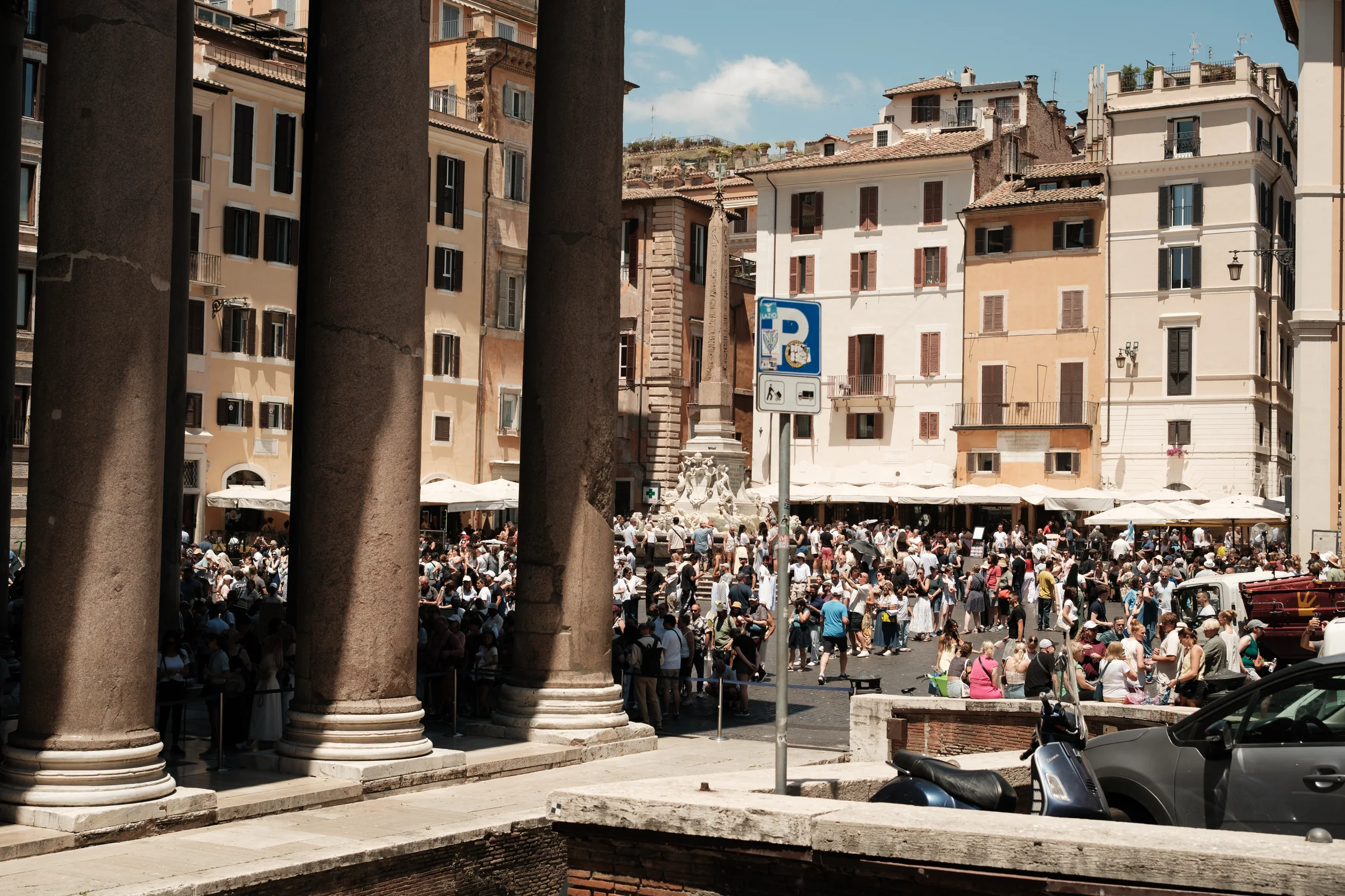 A crowded Roman square seen between monumental stone columns