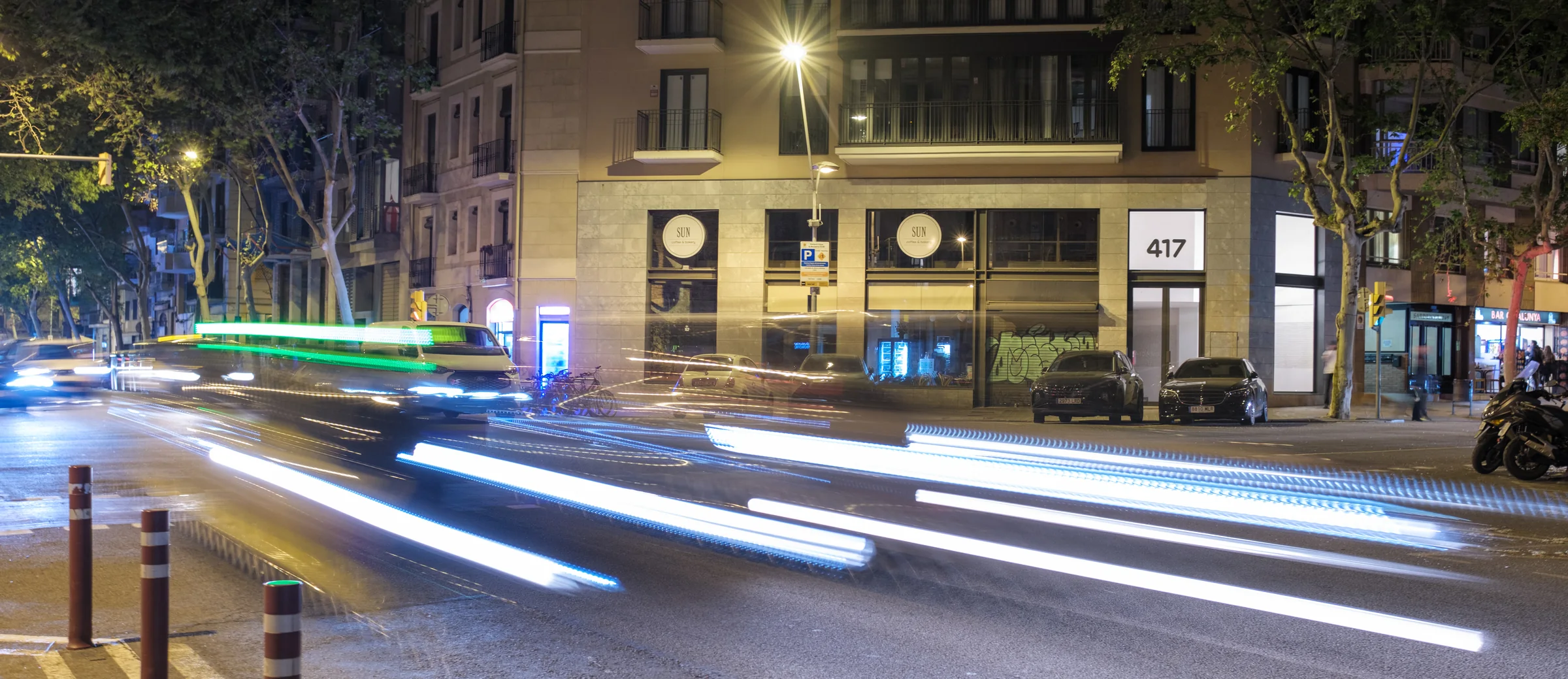 Night traffic leaves bright light trails across a Barcelona intersection